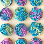 Decorative cupcakes with swirl patterns in blue, pink, and purple on a light background